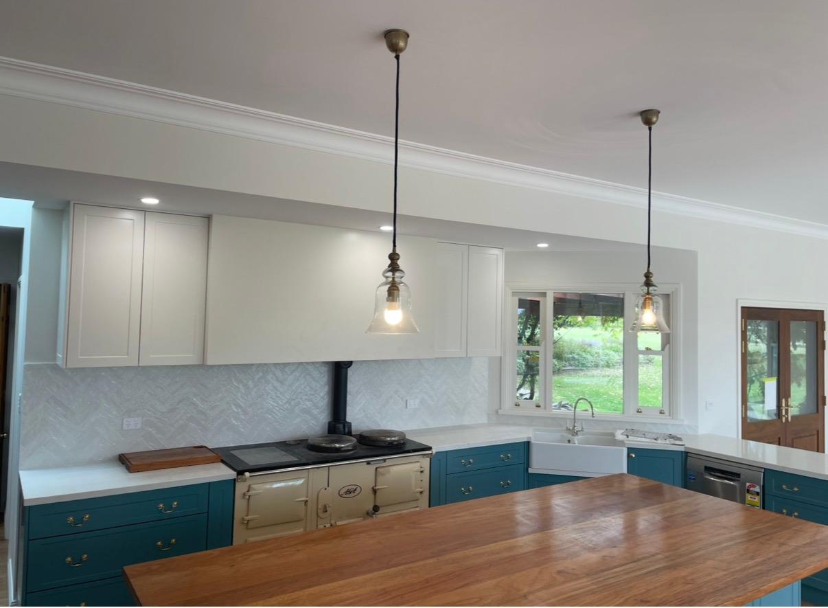 Country kitchen with teal cabinetry, range cooker and timber island bench