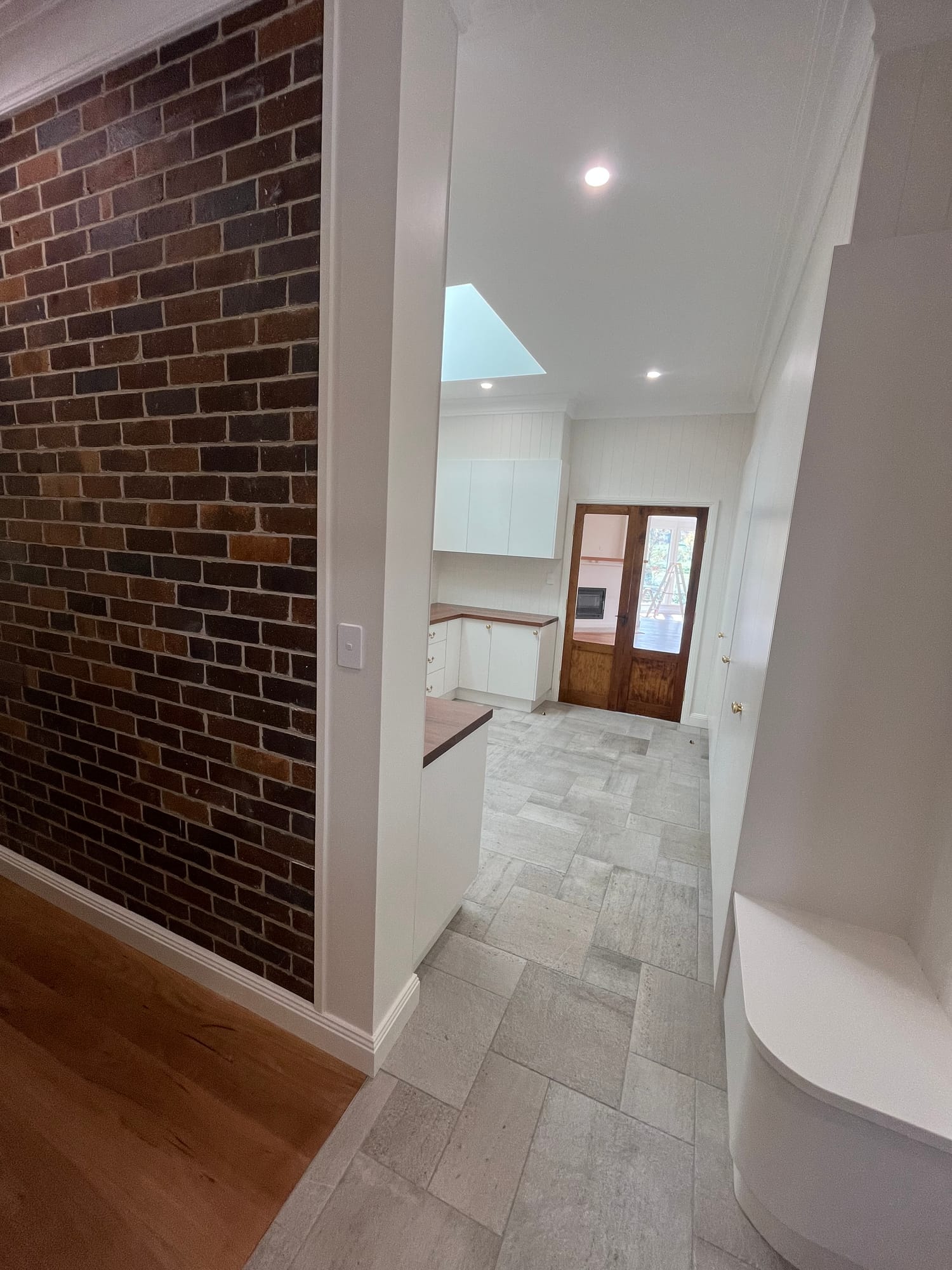 Open living area with exposed brick wall and new kitchen