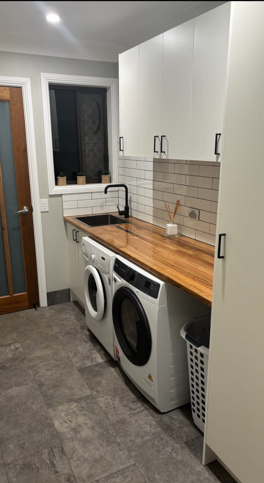 Laundry with timber benchtop, subway tiles and built-in cabinetry